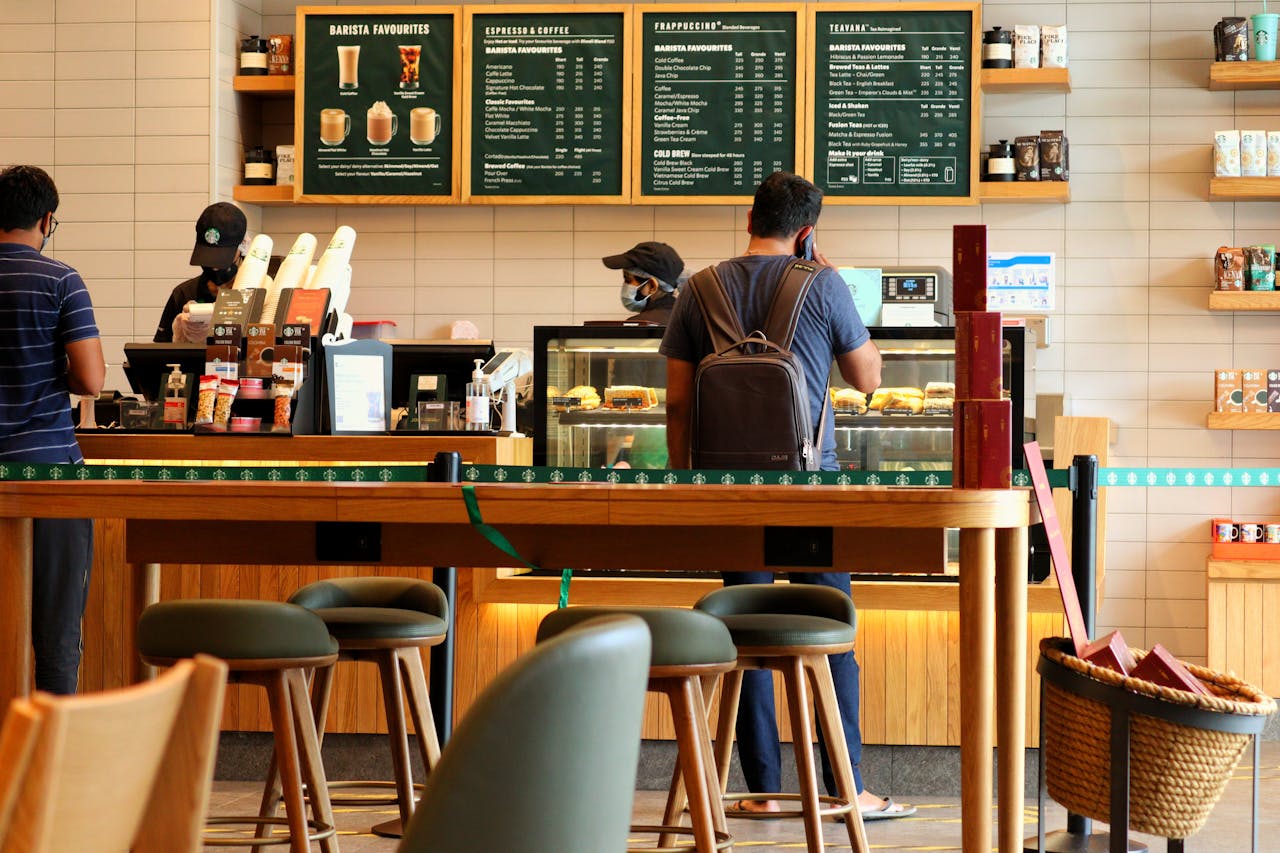 Customers at a bustling coffee shop counter ordering drinks and pastries.