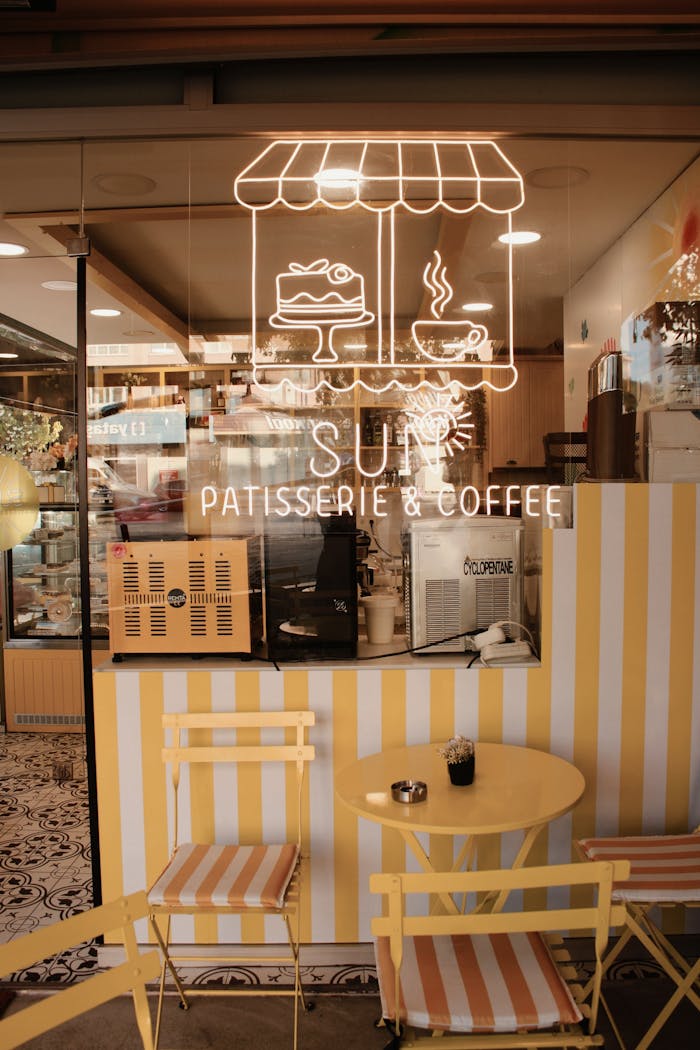 Charming outdoor cafe with a neon sign displaying desserts and coffee on a sunny day.